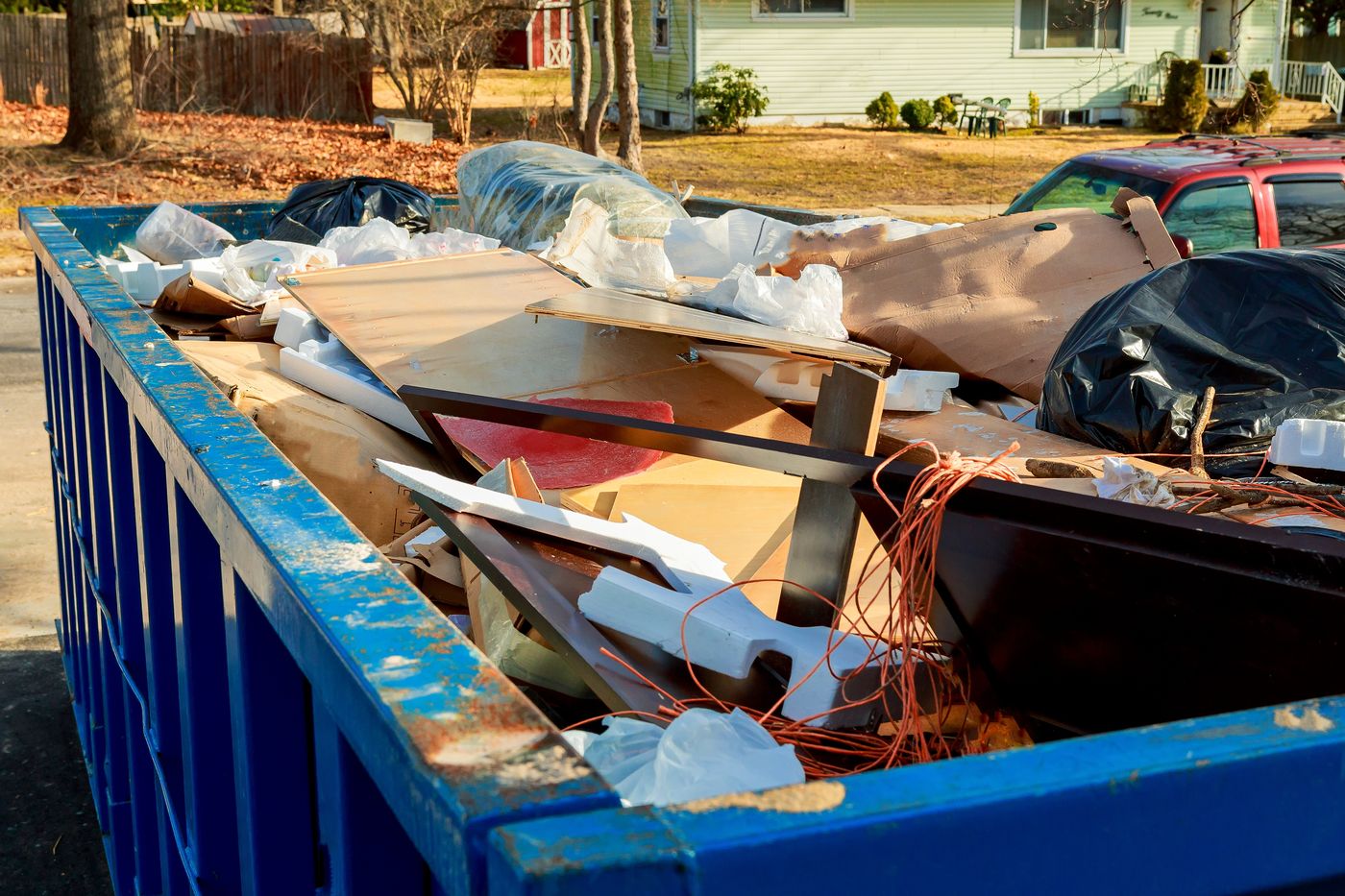 Dumpster filled with household junk in a suburban driveway